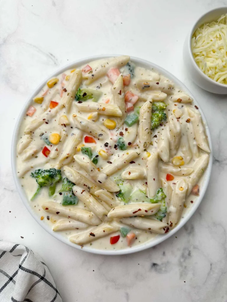 Creamy white sauce pasta with mixed vegetables, herbs, and cheese