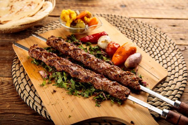 Juicy grilled kebabs on skewers garnished with coriander and lemon Image Title: