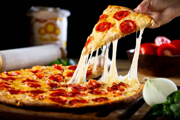 Fresh homemade pizza topped with mozzarella cheese, capsicum, onions, sweet corn, mushrooms, and olives served on a wooden board