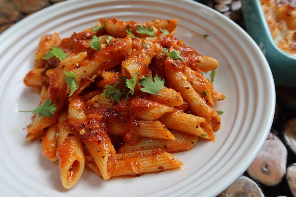 Bowl of red sauce pasta garnished with fresh basil and grated cheese